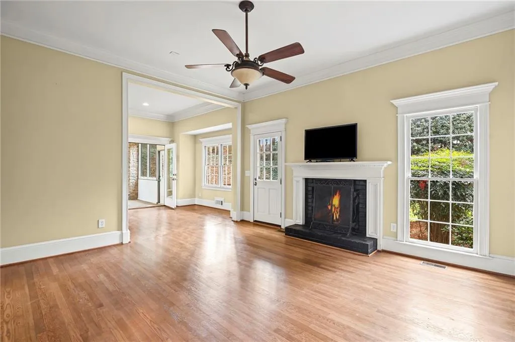 Unfurnished living room with ornamental molding, a lit fireplace, light wood-style floors, and a ceiling fan