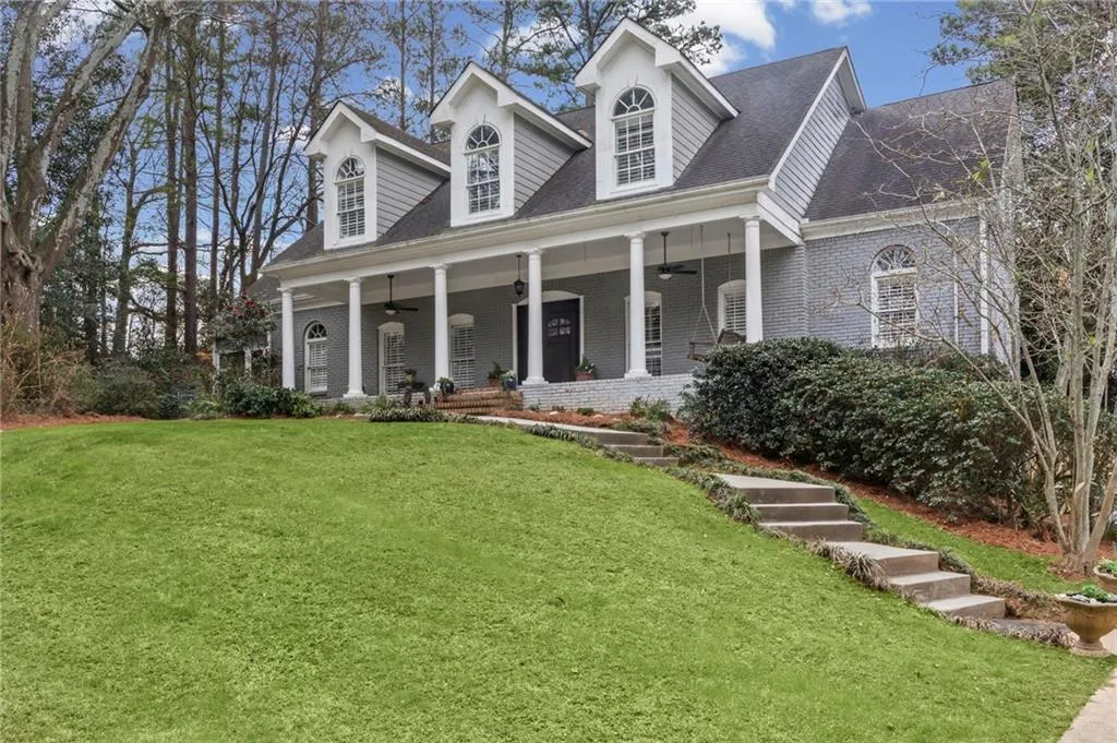 Cape cod house featuring covered porch, roof with shingles, brick siding, and a front yard