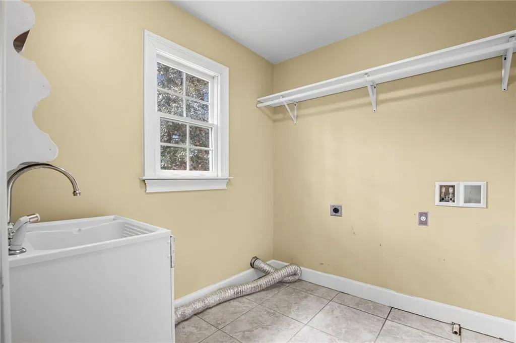 Laundry room featuring hookup for an electric dryer, light tile patterned floors, and washer hookup