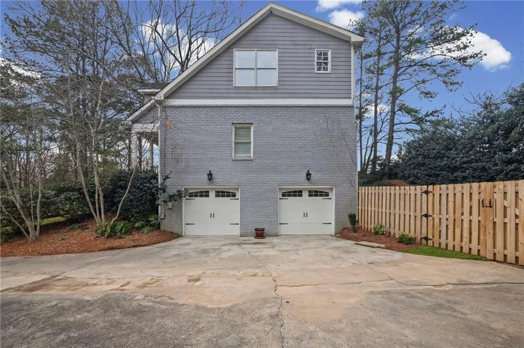 View of side of home featuring driveway, brick siding, and an attached garage