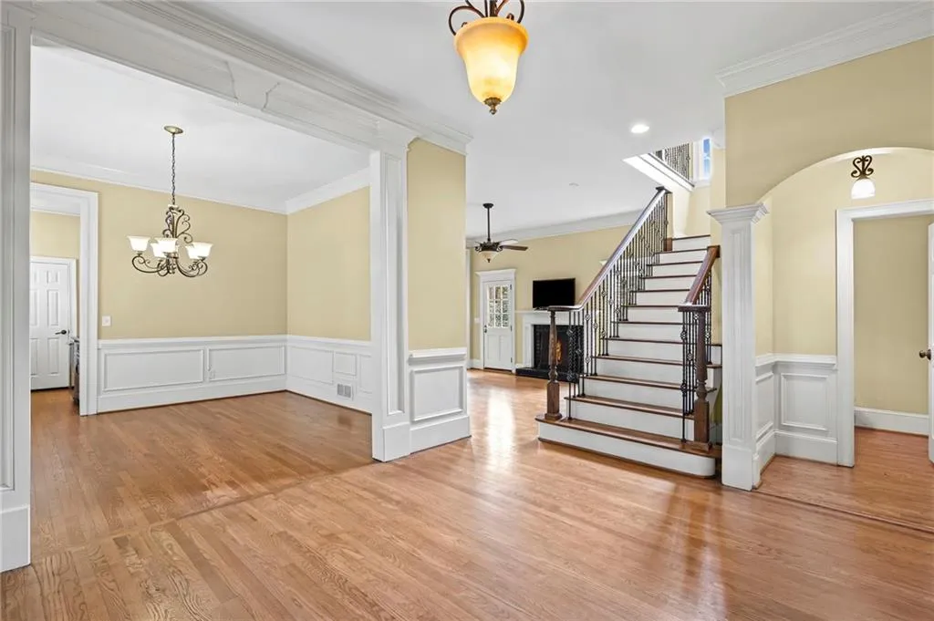 Foyer featuring crown molding, wainscoting, hanging lights, a warm lit fireplace, and light wood-type flooring