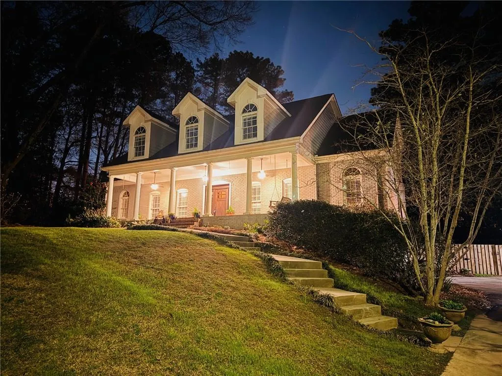 Cape cod house with covered porch, brick siding, and a lawn