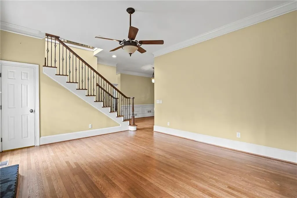 Unfurnished living room with crown molding, light wood finished floors, and ceiling fan