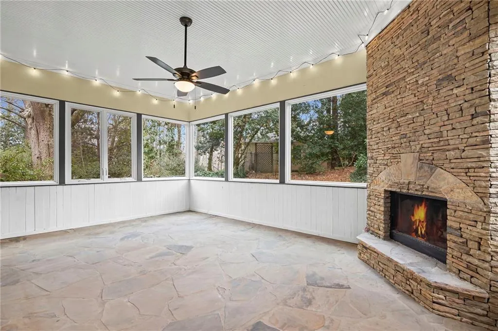 Unfurnished sunroom with a fireplace, ceiling fan, and rail lighting