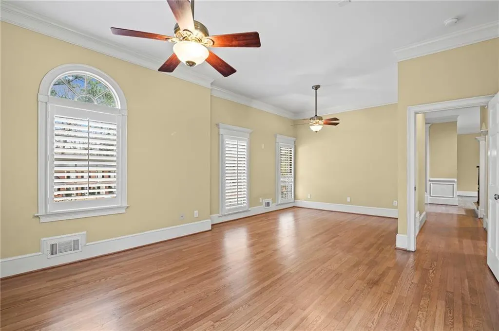 Spare room featuring hardwood / wood-style floors, ceiling fan, and crown molding