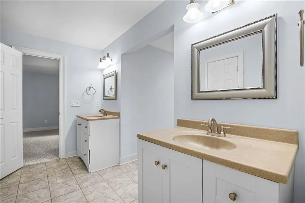 Full bath featuring two vanities and light tile patterned floors