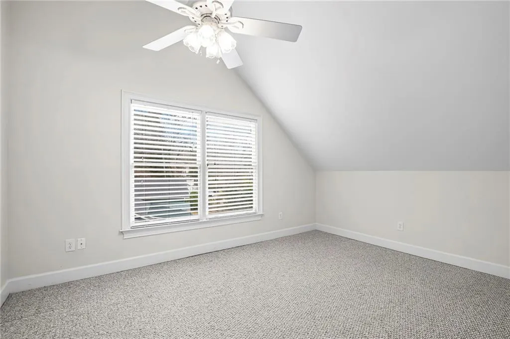 Additional living space with lofted ceiling, light carpet, and ceiling fan