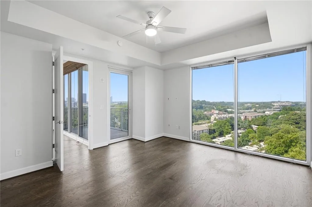 Primary Bedroom. Balcony access. Spacious room featuring floor-to-ceiling windows, dark wood-finish flooring, a ceiling fan, and direct access to a private balcony