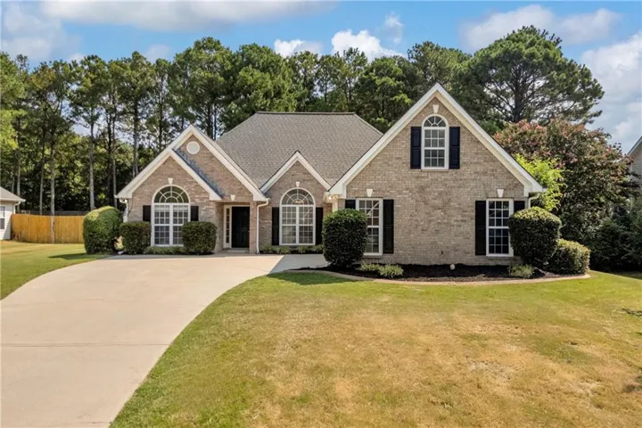 Brick exterior with a dark-toned roof, arched windows, and a concrete driveway