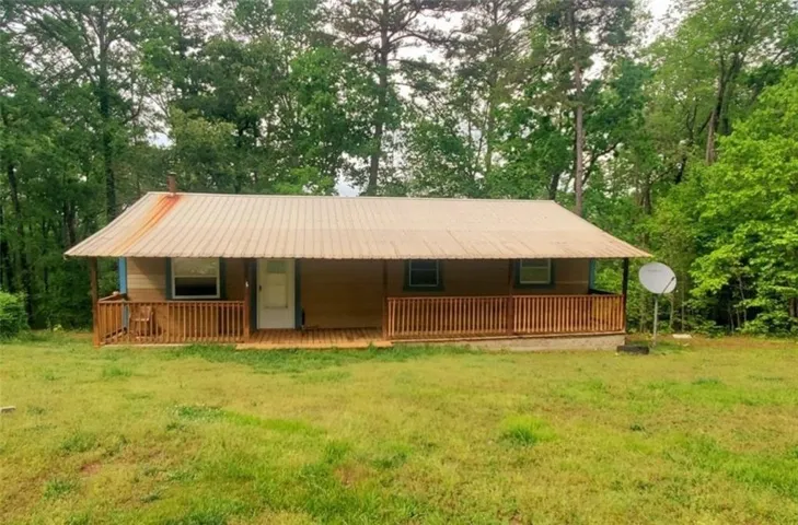 View of front of house with a front yard, view of scattered trees, and a metal roof