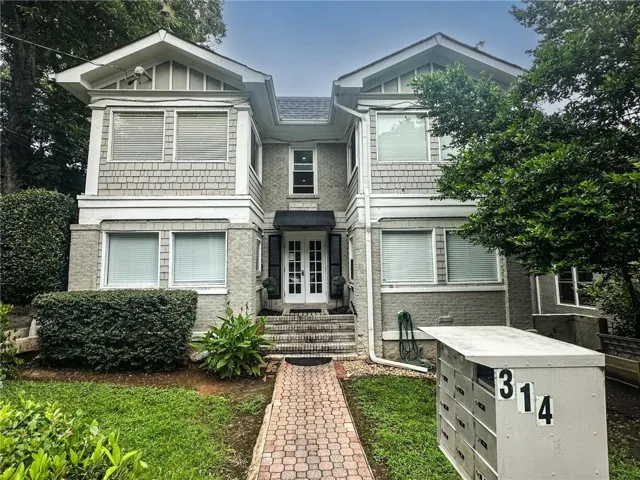 Elegant two-story residence featuring a symmetrical façade with white shingle and stone exterior cladding, gabled rooflines with architectural detailing, and multi-pane windows throughout