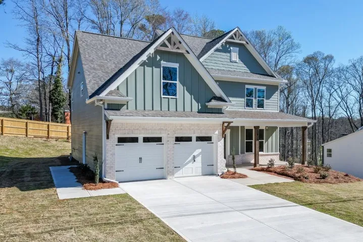Contemporary two-story residence featuring a two-car garage, light brick detailing, board and batten siding, and a covered front porch with substantial wood columns