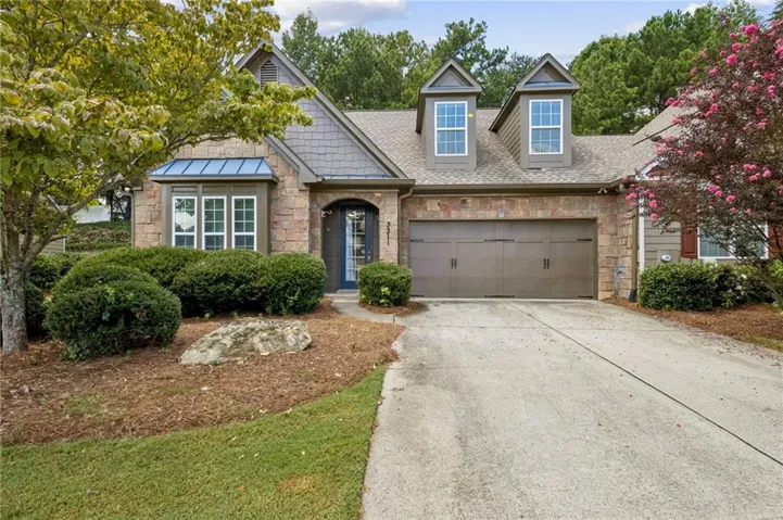 Stone and siding exterior with a two-car garage, dormer windows, and a bay window with a metal roof accent