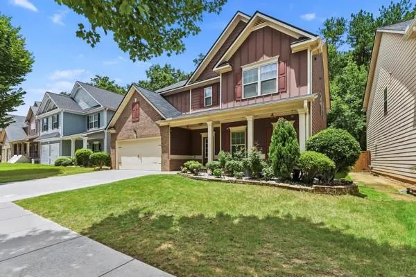 Two-story residence featuring a combination of brick and siding, a two-car garage, and a covered front porch with white columns