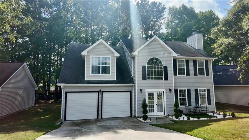 Two-story residence featuring light gray siding, a two-car garage, a prominent arched window, and a double-door entry