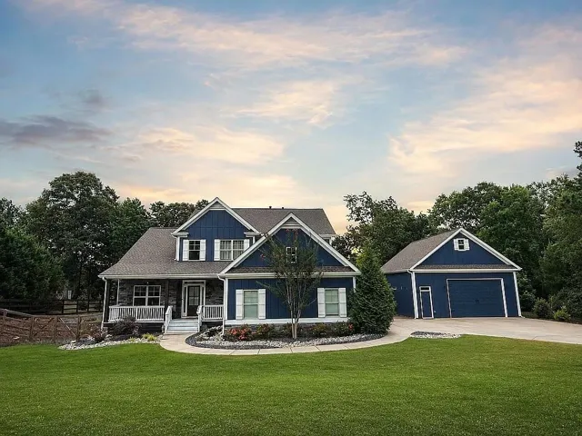 Two-story home featuring a deep blue siding exterior, stone accents, and white trim