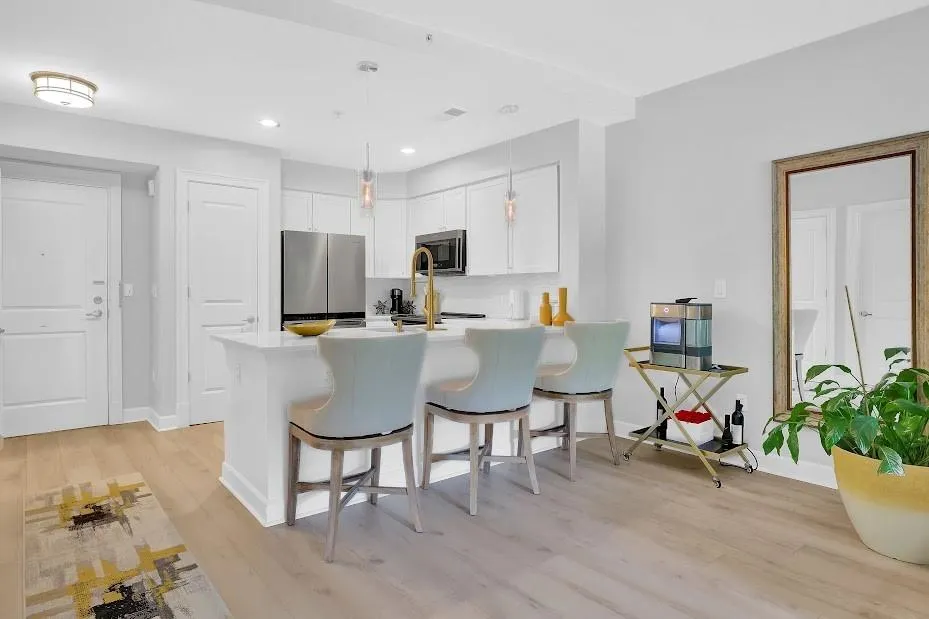 Kitchen with appliances with stainless steel finishes, light hardwood / wood-style flooring, a breakfast bar, white cabinetry, and pendant lighting