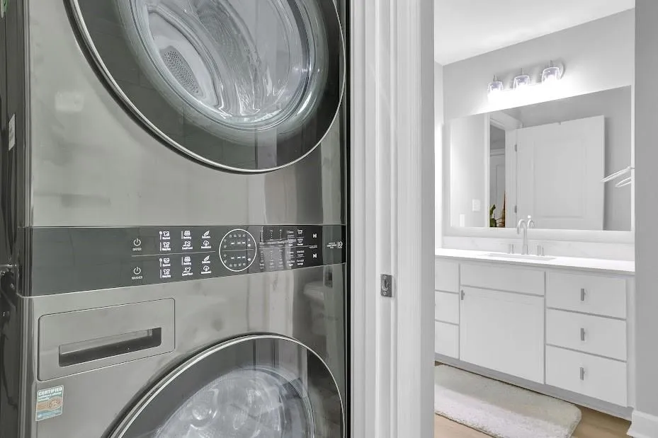 Washroom with sink, stacked washing maching and dryer, and light hardwood / wood-style floors