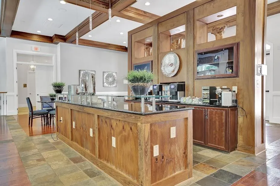 Kitchen with a kitchen island with sink, pendant lighting, coffered ceiling, beam ceiling, and dark stone countertops