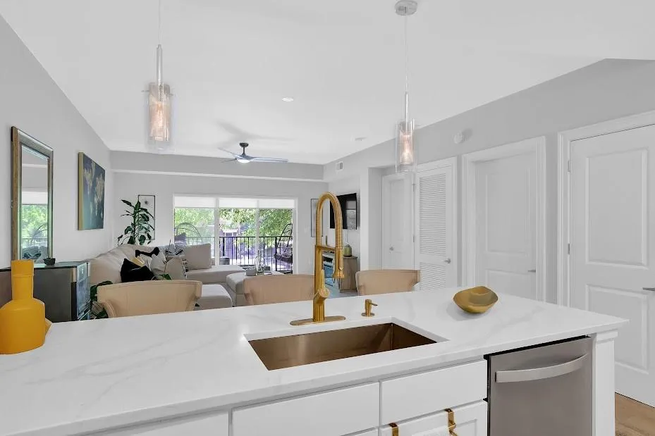 Kitchen with sink, pendant lighting, stainless steel dishwasher, light stone counters, and ceiling fan