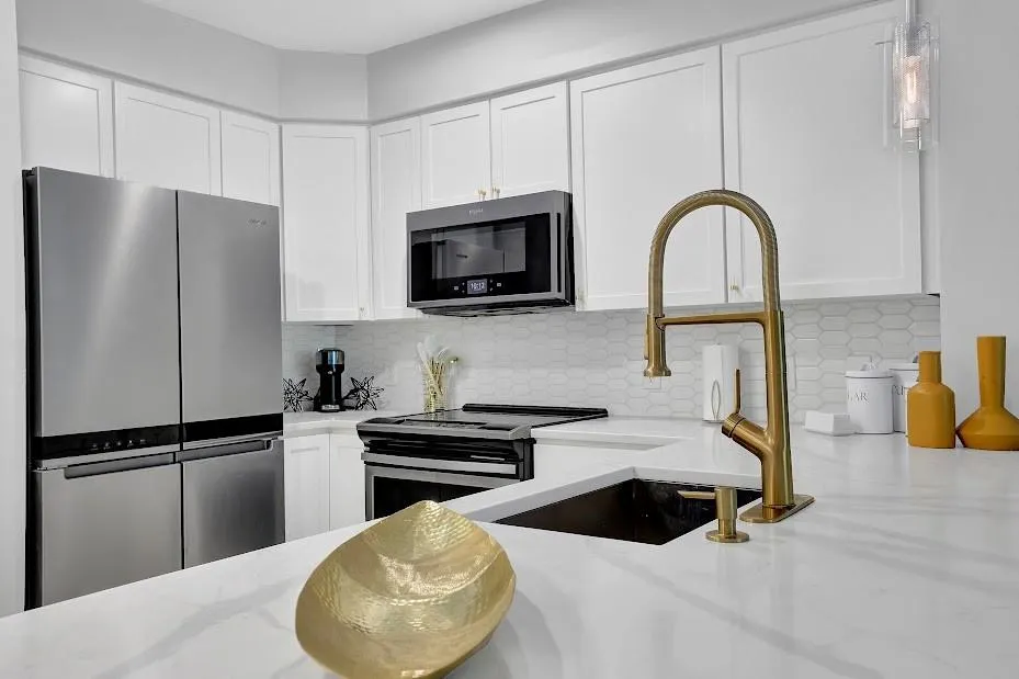 Kitchen with tasteful backsplash, stainless steel appliances, white cabinetry, sink, and light stone countertops