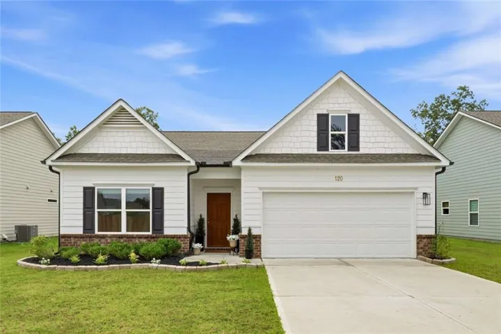 White siding exterior with brick accents, attached two-car garage, manicured landscaping, and a covered entryway