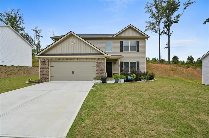View of front of home with brick siding, concrete driveway, a front yard, and board and batten siding