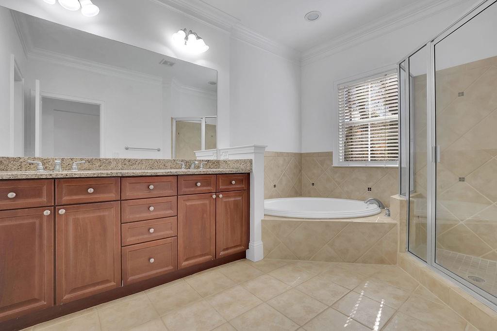 Bathroom with dual vanity, ornamental molding, tile floors, and independent shower and bath