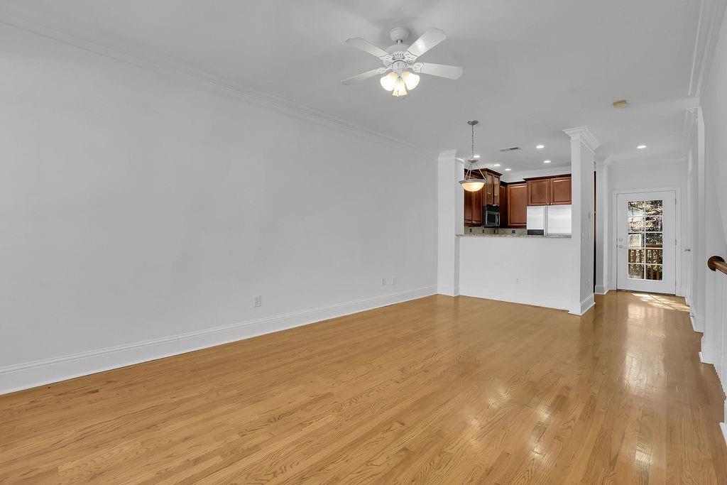 Unfurnished living room featuring light hardwood / wood-style flooring, ceiling fan, and crown molding