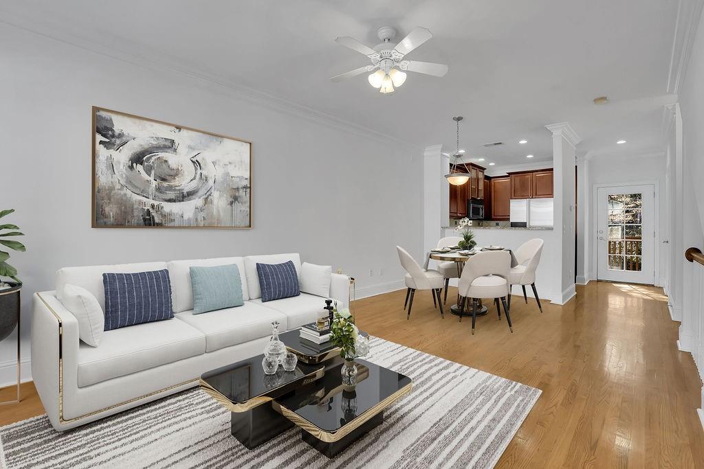 Living room with light wood-type flooring, ceiling fan, and ornamental molding