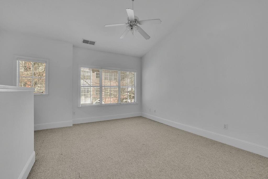 Spare room with vaulted ceiling, ceiling fan, and light carpet