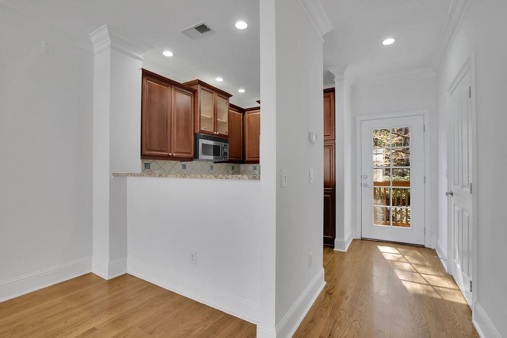 Kitchen with light wood-type flooring, ornamental molding, light stone counters, and backsplash