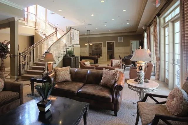 Carpeted living room featuring crown molding, brick wall, and a towering ceiling