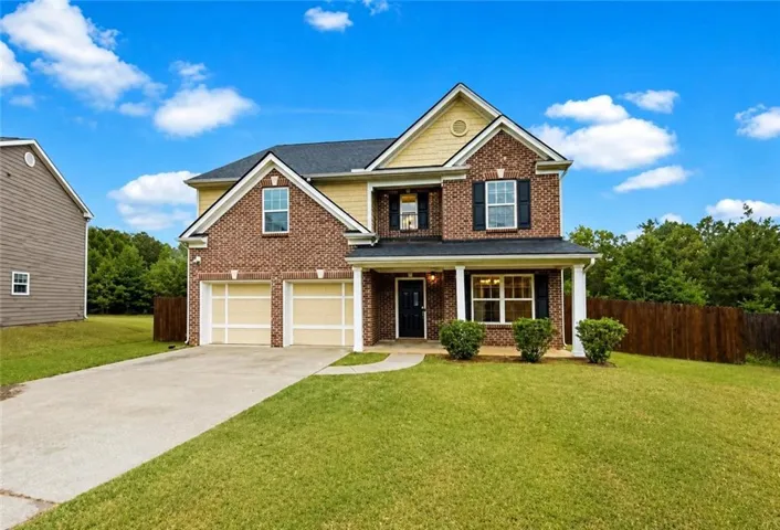 Brick and siding exterior with a covered porch, two-car garage, and fenced backyard