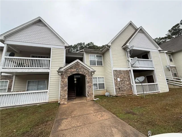 View of front of house with stone siding and a balcony