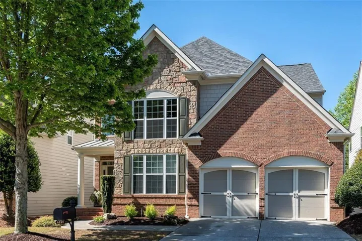 Brick and stone facade, arched garage doors, two-car garage, established landscaping, prominent front entry