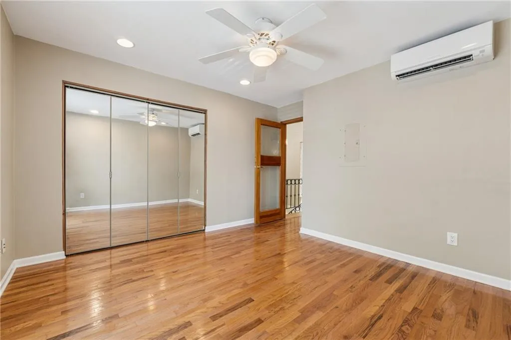 Unfurnished bedroom featuring a wall mounted air conditioner, recessed lighting, light wood-style floors, a closet, and ceiling fan