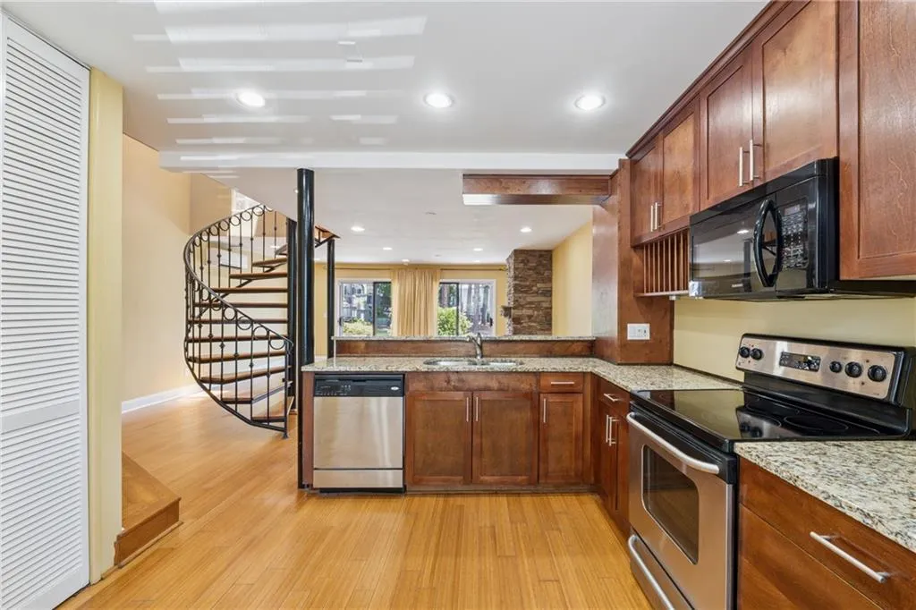 Kitchen with appliances with stainless steel finishes, light wood finished floors, light stone counters, a peninsula, and recessed lighting