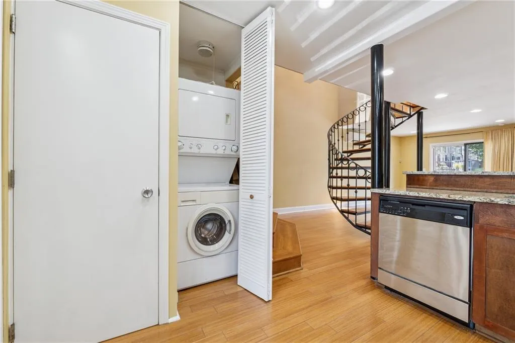 Laundry room with stacked washer / dryer, light wood-style floors, and recessed lighting