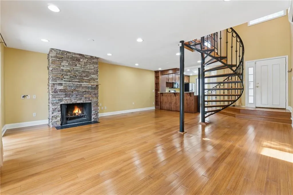 Unfurnished living room featuring a fireplace, stairs, light wood-style floors, and recessed lighting