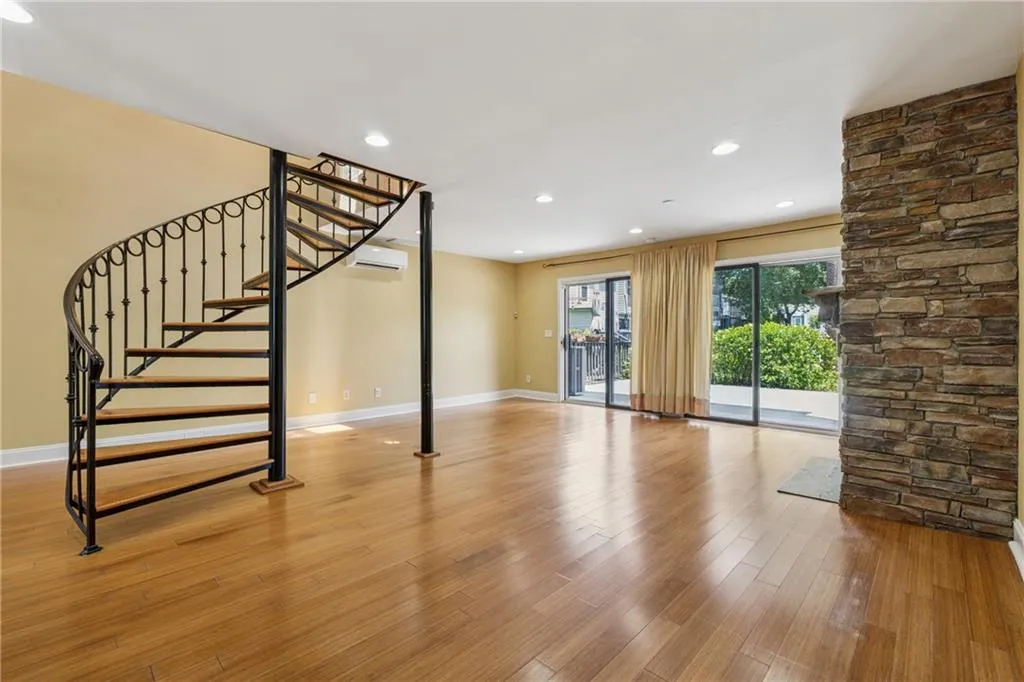 Unfurnished living room featuring wood finished floors, stairway, recessed lighting, and an AC wall unit