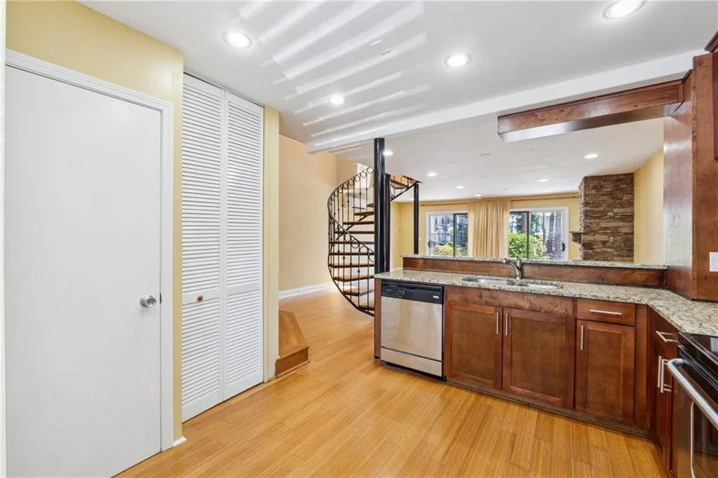 Kitchen with stainless steel dishwasher, light wood-style flooring, light stone counters, range, and recessed lighting
