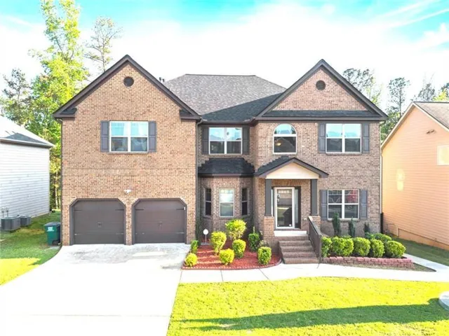 Brick exterior, two-car garage, covered front entry, arched windows, and established landscaping