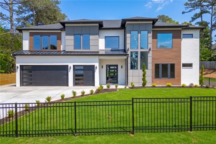 Contemporary exterior with white stucco, wood-finish paneling, and a black metal fence