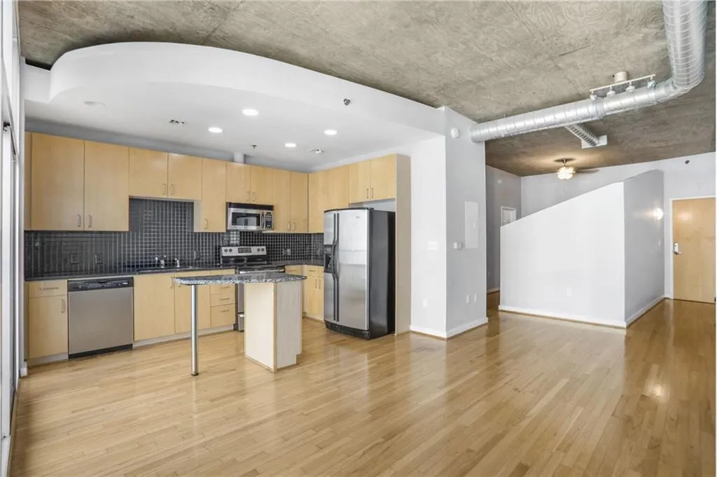Kitchen featuring open floor plan, light brown cabinetry, light wood-type flooring, and appliances with stainless steel finishes
