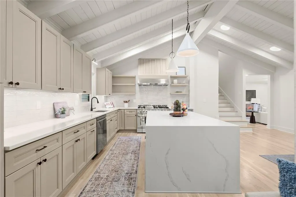 Kitchen featuring open shelves, a kitchen island, light wood finished floors, appliances with stainless steel finishes, and pendant lighting
