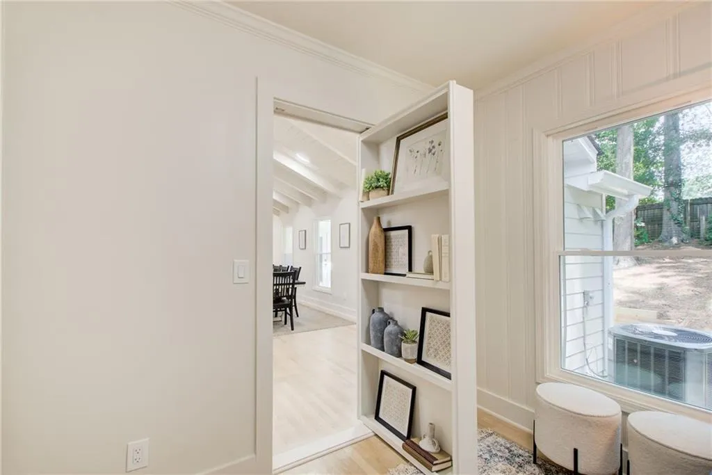 Living area featuring light wood-style floors, healthy amount of natural light, and ornamental molding