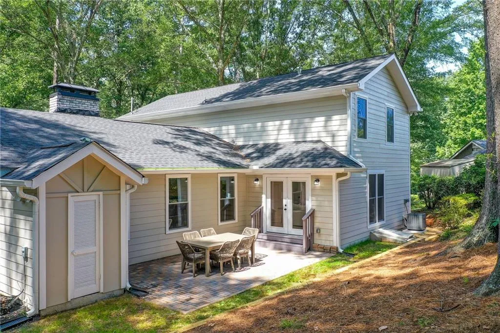 Rear view of property featuring french doors, a patio, a chimney, and roof with shingles