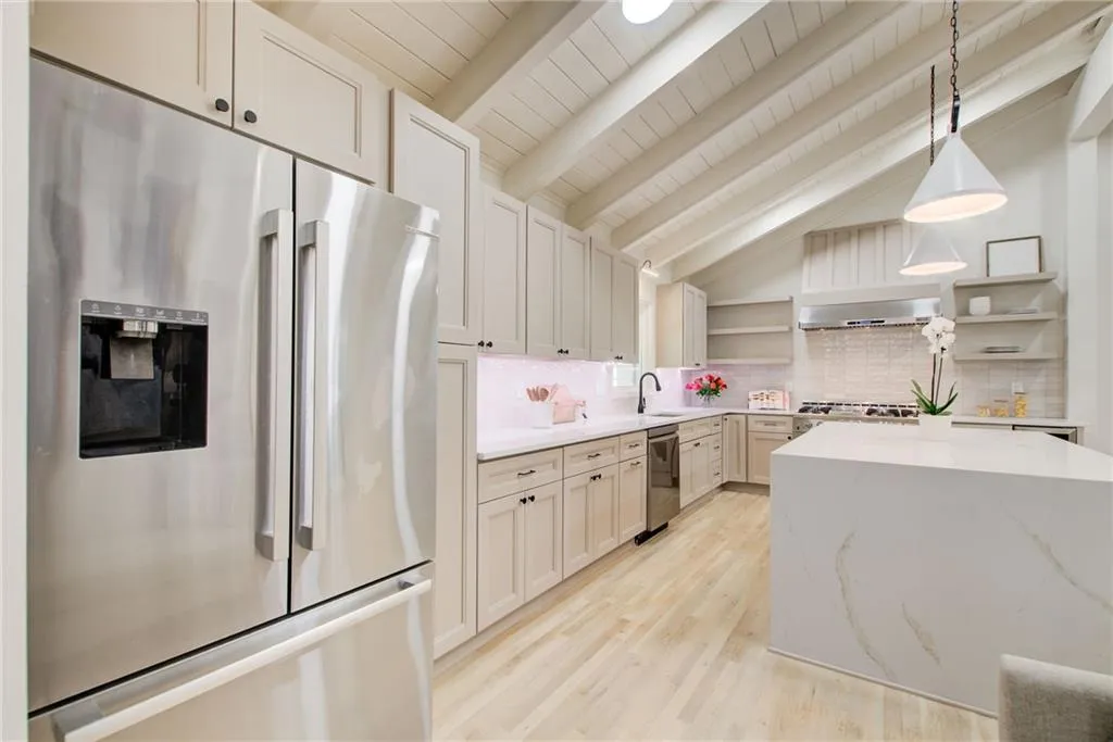 Kitchen with open shelves,  stainless steel appliances, wood flooring, decorative backsplash, and decorative light fixtures