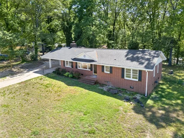 Brick ranch-style residence featuring a dark shingle roof and white trim